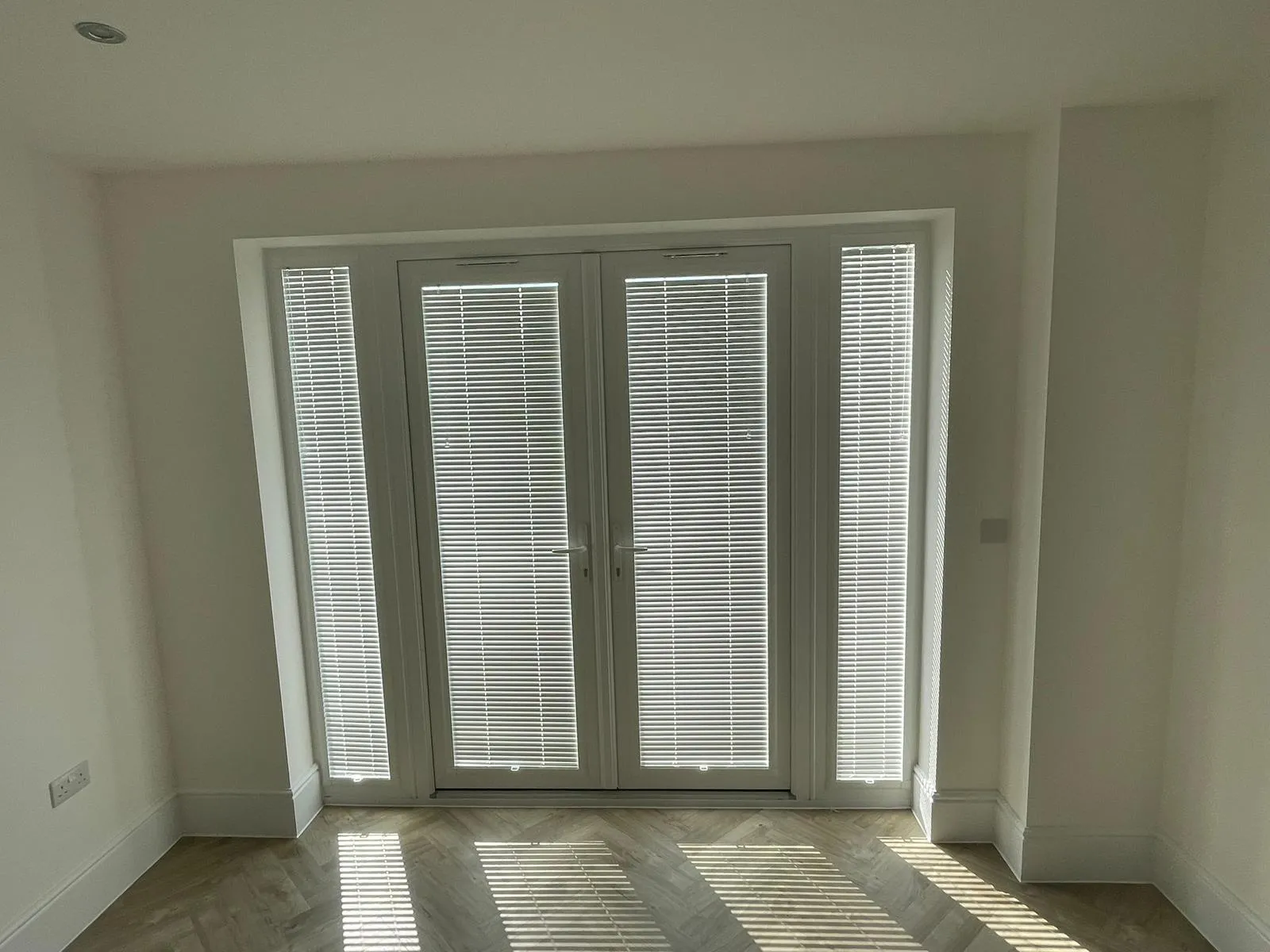 White venetian blinds fitted to french doors and their side windows
