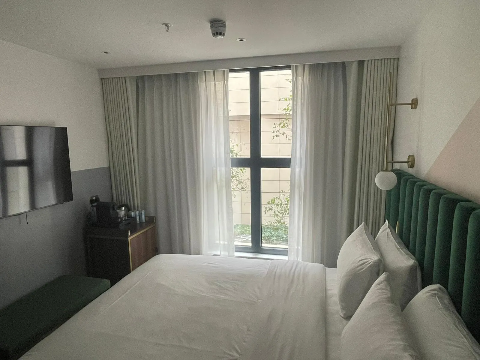 Wall-to-wall grey curtains and white sheers behind the bed in a hotel bedroom